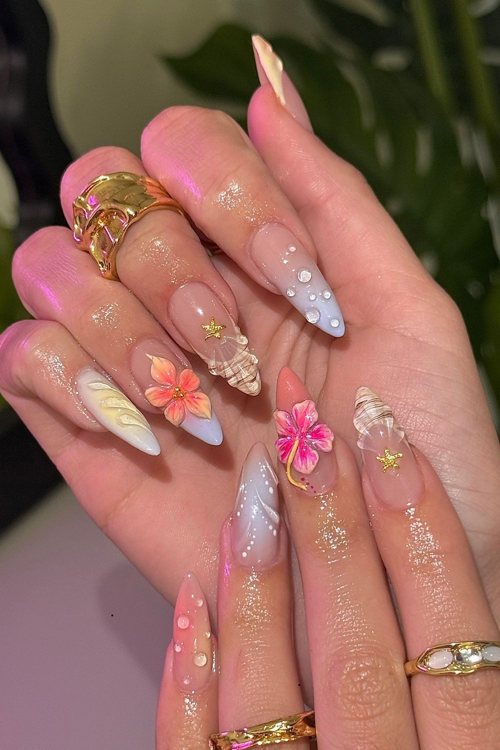 Summer 2025 nail art with 3D flowers, seashells, starfish, and water drops. Long pointed nails with pastel colors perfect for summer looks.