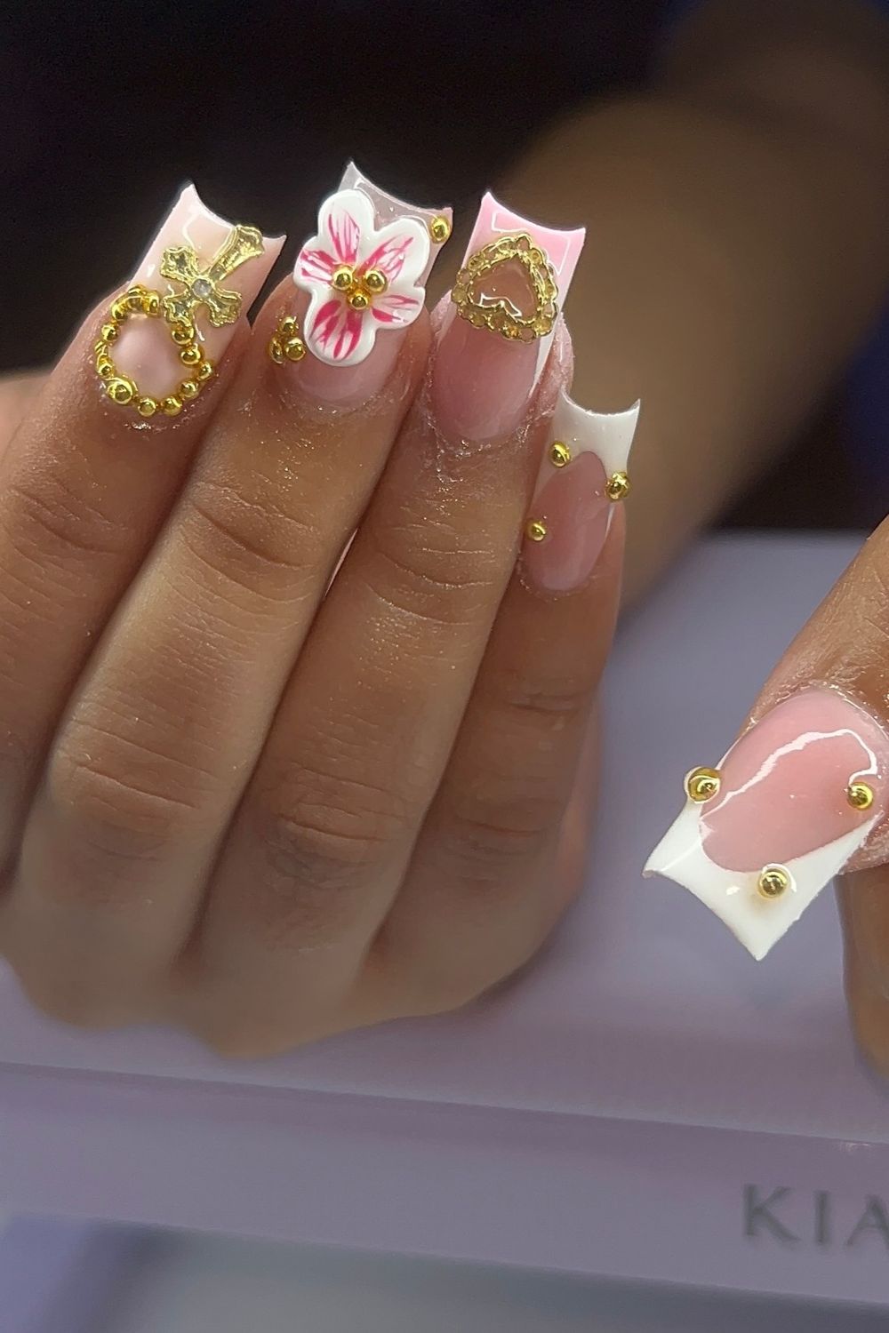 Summer 2025 pink and white nail art with gold charms and beads.